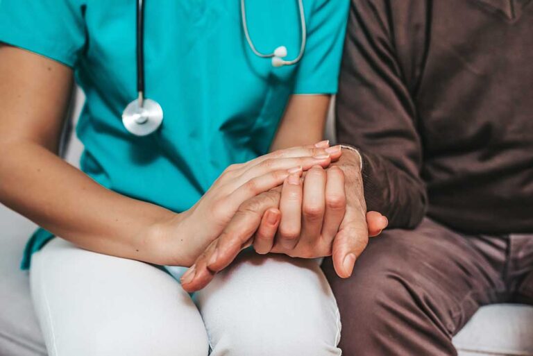 An older adult and a caregiver sitting together reviewing a care plan document at a table.